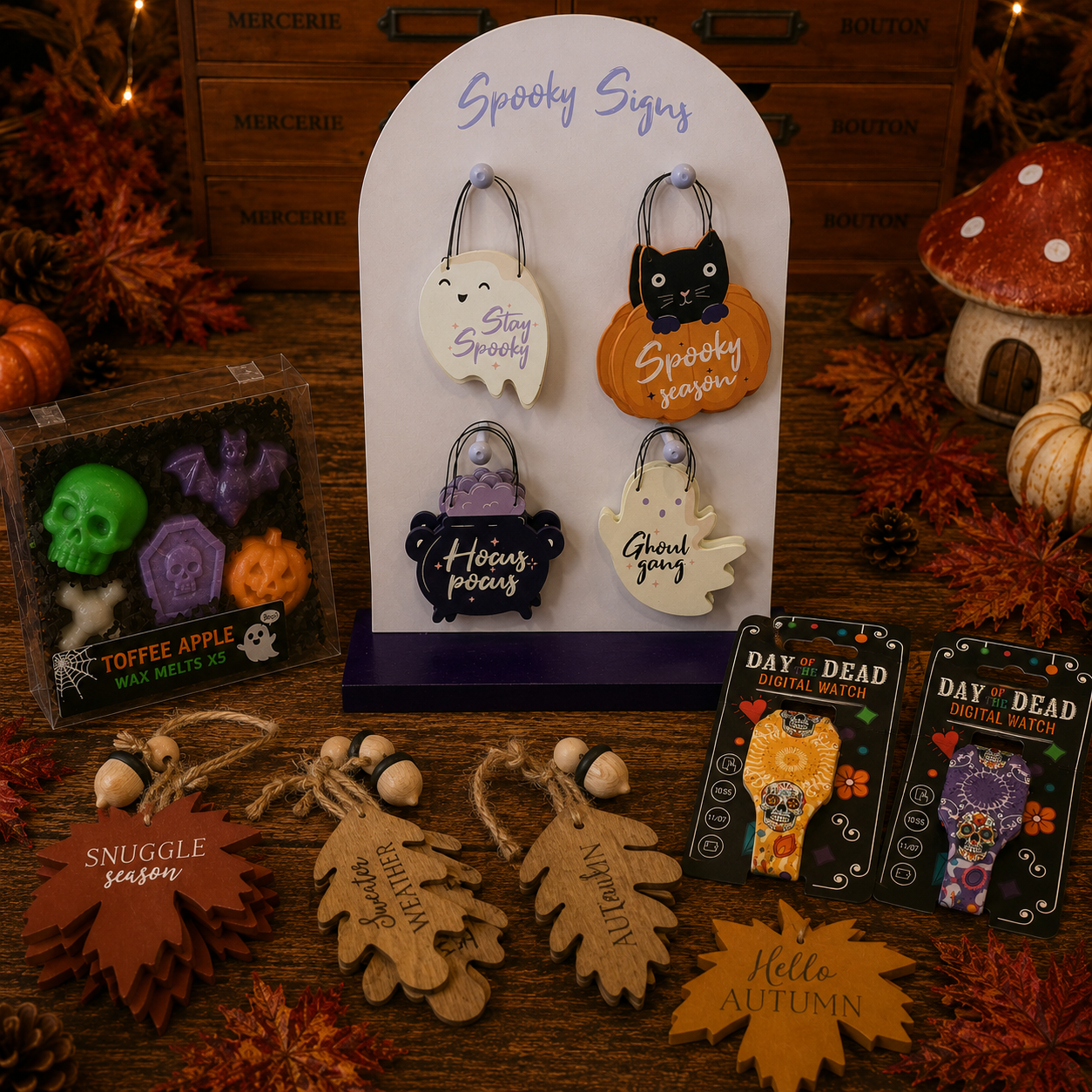 A styled tabletop display of Halloween-themed wax melts and tags. In the center is an arched white stand labeled 'Spooky Signs' holding four wax melts shaped like a ghost, pumpkin, cat, and moon.